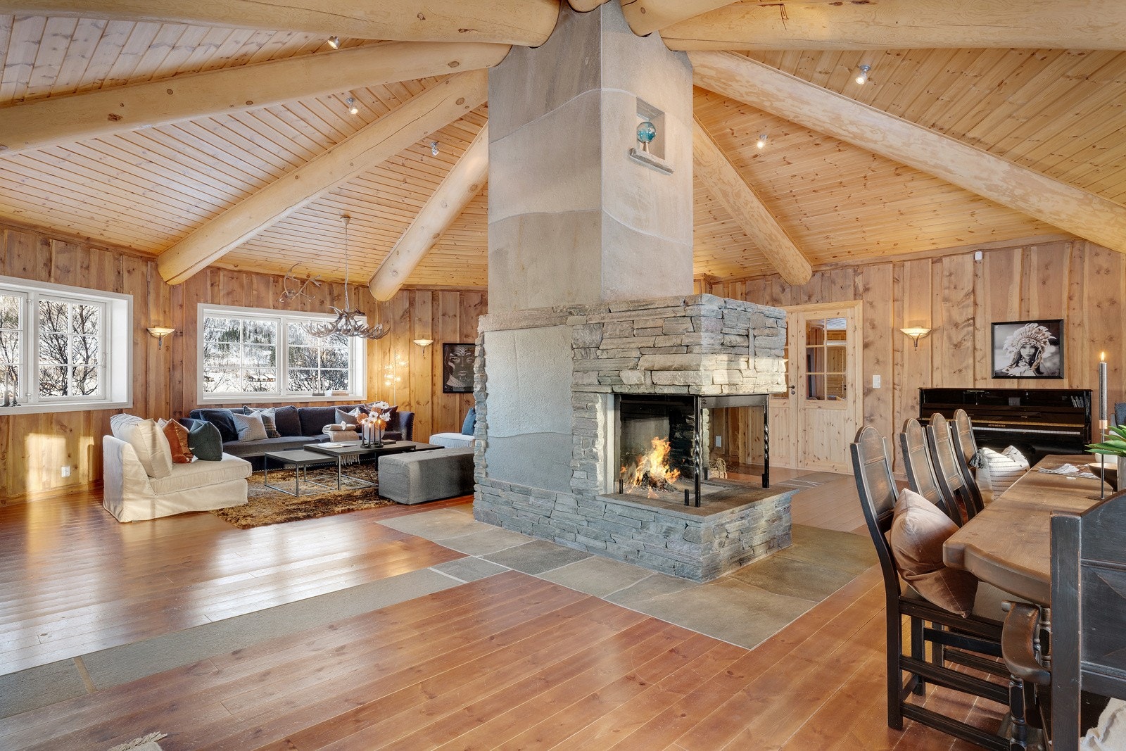 Flott plassbygget peis har sin plassering midt i stuen og fungerer som en naturlig romdeler. Peisen gir et naturlig skille mellom stue, kjøkken og spisestue. Galleribilde