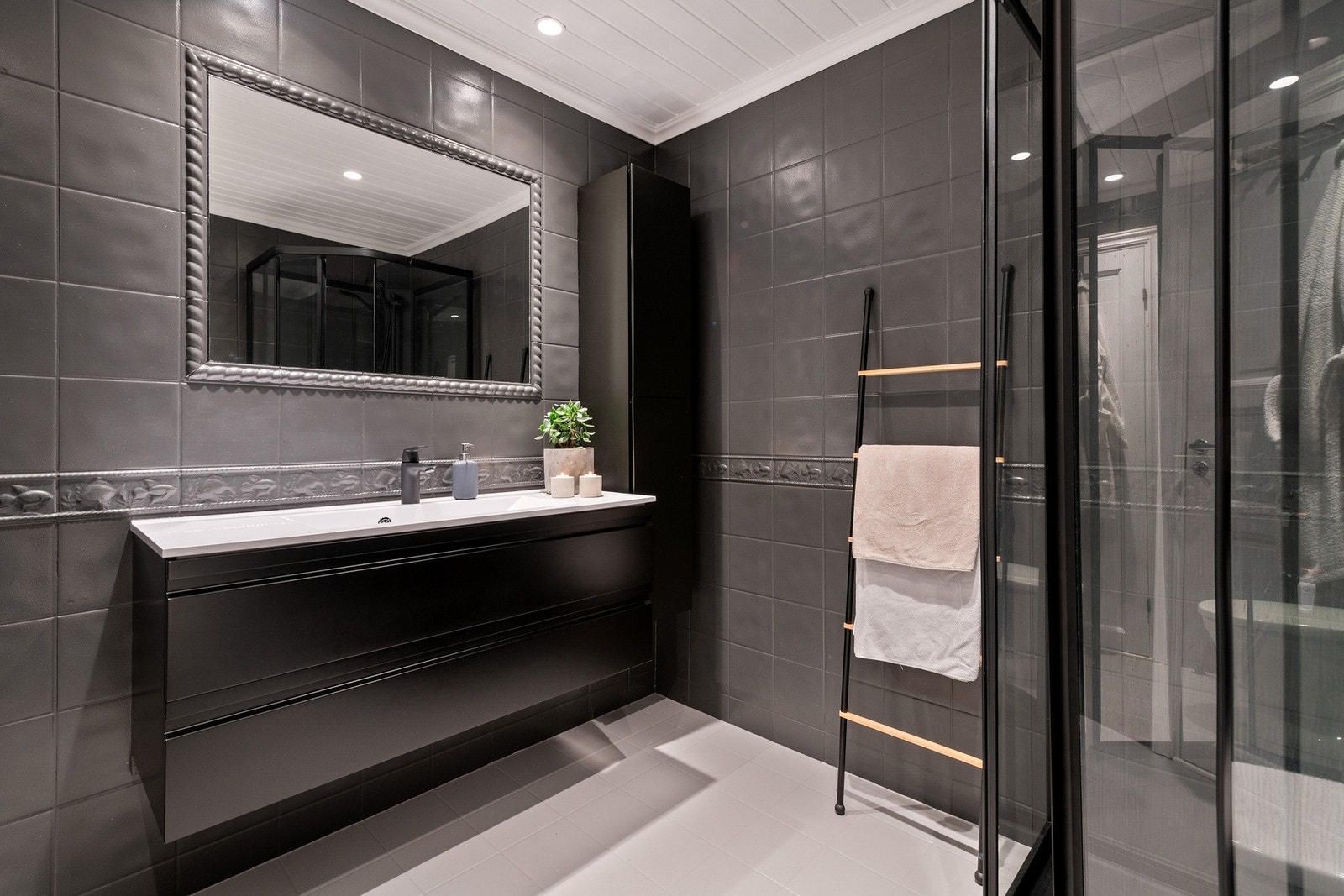 Flislagt baderom. Rommet inneholder: Dusjkabinett, servant med innredning og toalett. Galleribilde