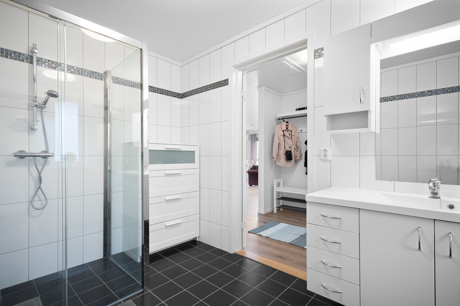 Badet er innredet med servantmøbler, ogverskap, vegghengt toalett og stort dusjhjørne. Galleribilde