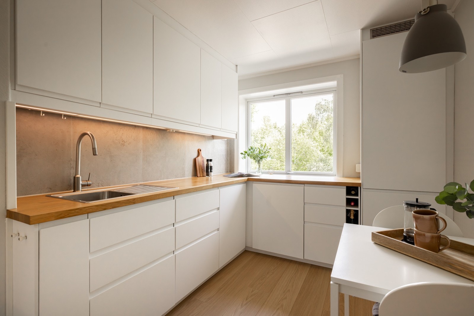 Stilrent og moderne kjøkken med innfreste håndtak og benkeplate i tre. Galleribilde