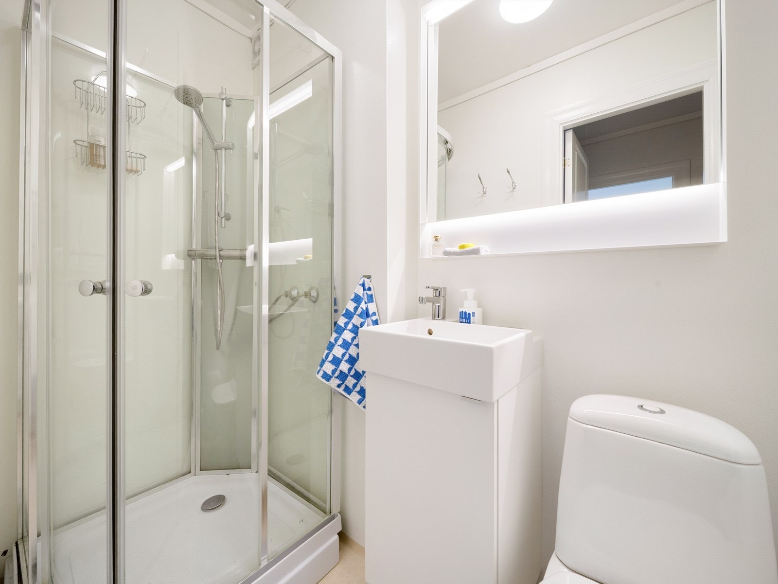 Eldre, men funksjonelt bad med dusjkabinett, toalett, servant og overskap med speil og lys Galleribilde