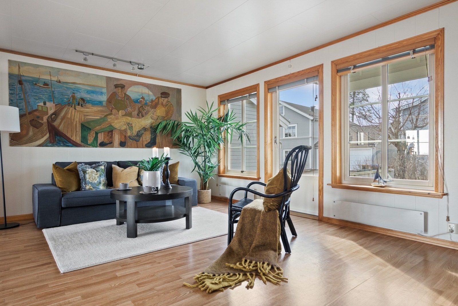 Allrommet har hvitmalte vegger, gylne heltredetaljer og belegg i parkettimitasjon på gulvet. Dagslyset strømmer inn via store vinduer, og det er utgang til uteplasser fra både stuen og kjøkkenet. Galleribilde