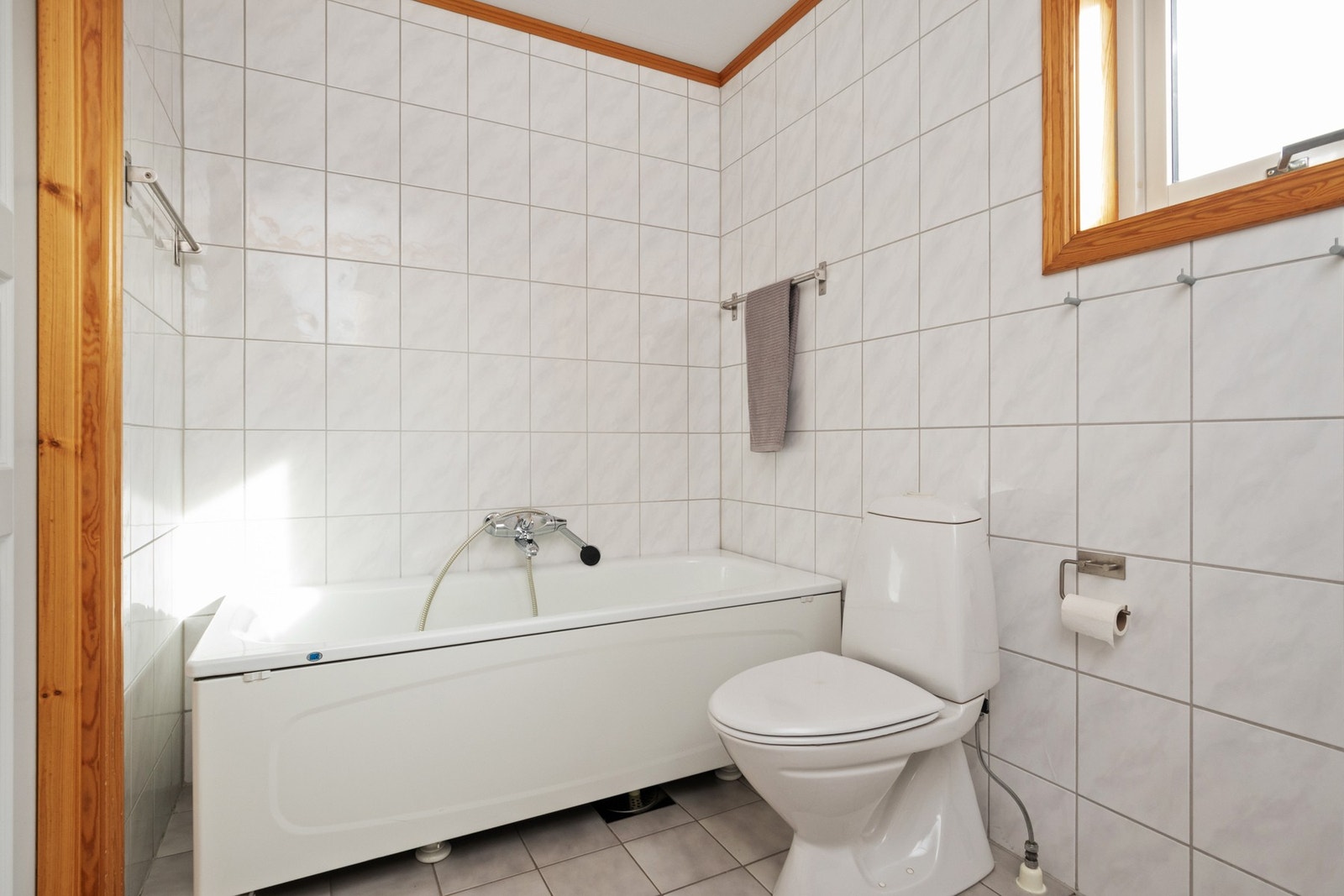 Badet har et toalett og et badekar med dusjarmatur. Galleribilde