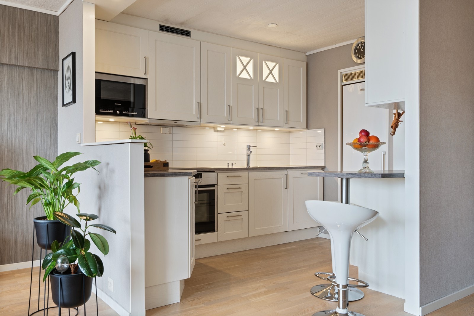 Lyst kjøkkeninnredning med integrerte hvitevarer. Galleribilde