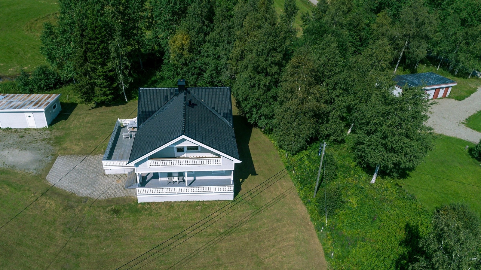 Dronebilde med hage og plen som går rundt hele huset Galleribilde