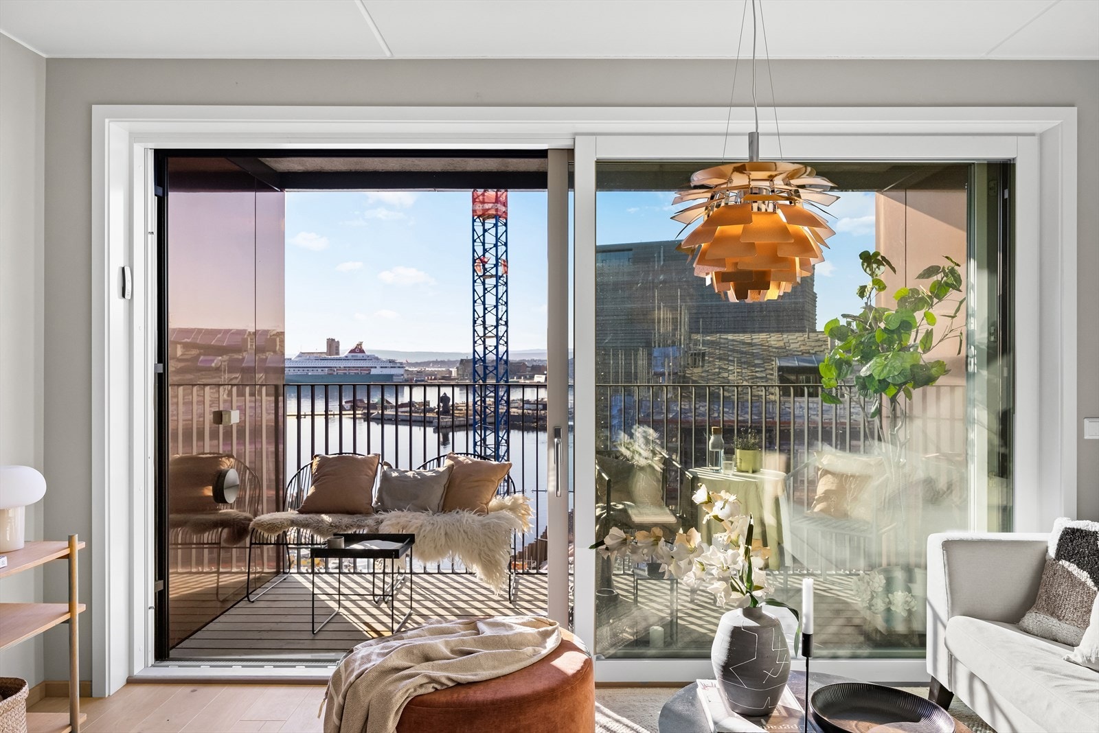 Flott skyvedør ut til solrik balkong og store glassfelt mot sjøen Galleribilde