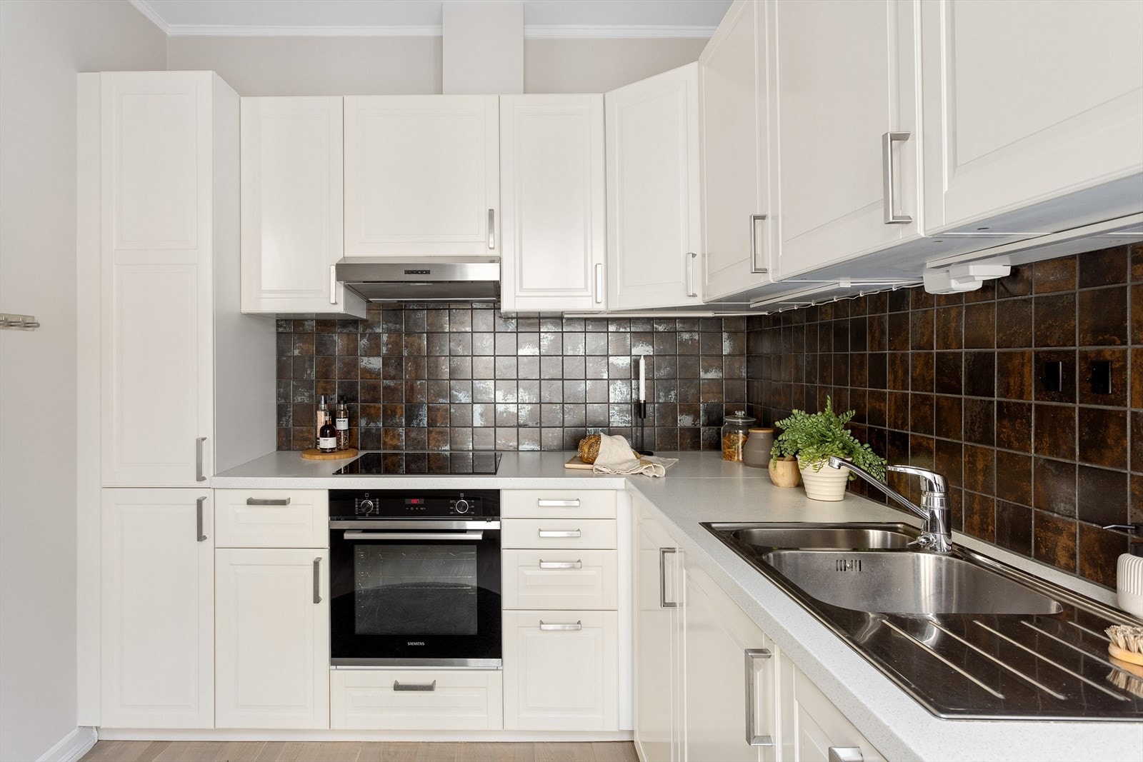 Kjøkkeninnredning med profilerte fronter, laminat benkeplate med nedfelt vaskekum. Integrert oppvaskmaskin, stekeovn og platetopp. Galleribilde