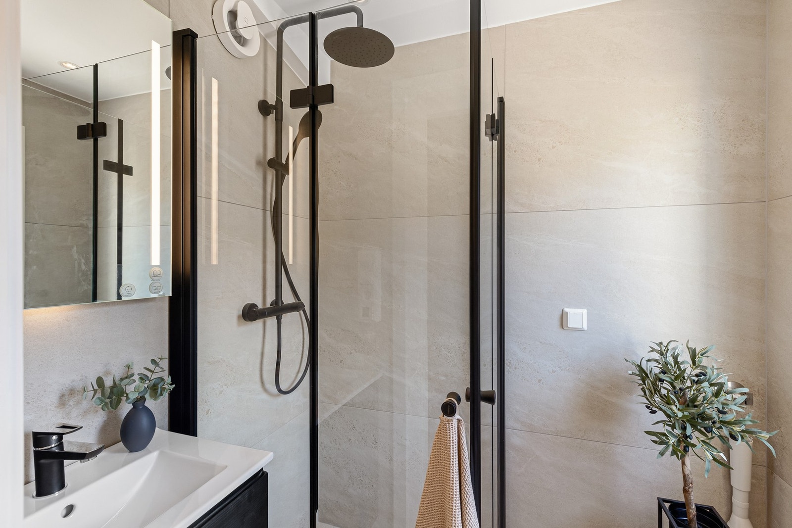 Delikat bad med dusjhjørne, baderomsinnredning og speil. Kran og avløp for vaskemaskin. Galleribilde