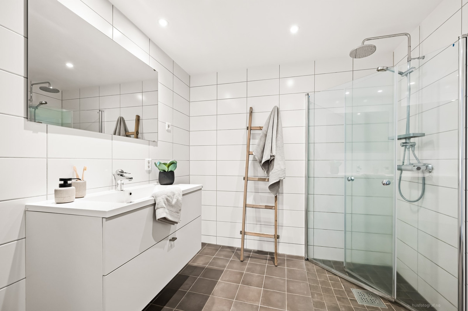 Badet har dusjhjørne med foldedører av glass samt regnfallsdusj Galleribilde