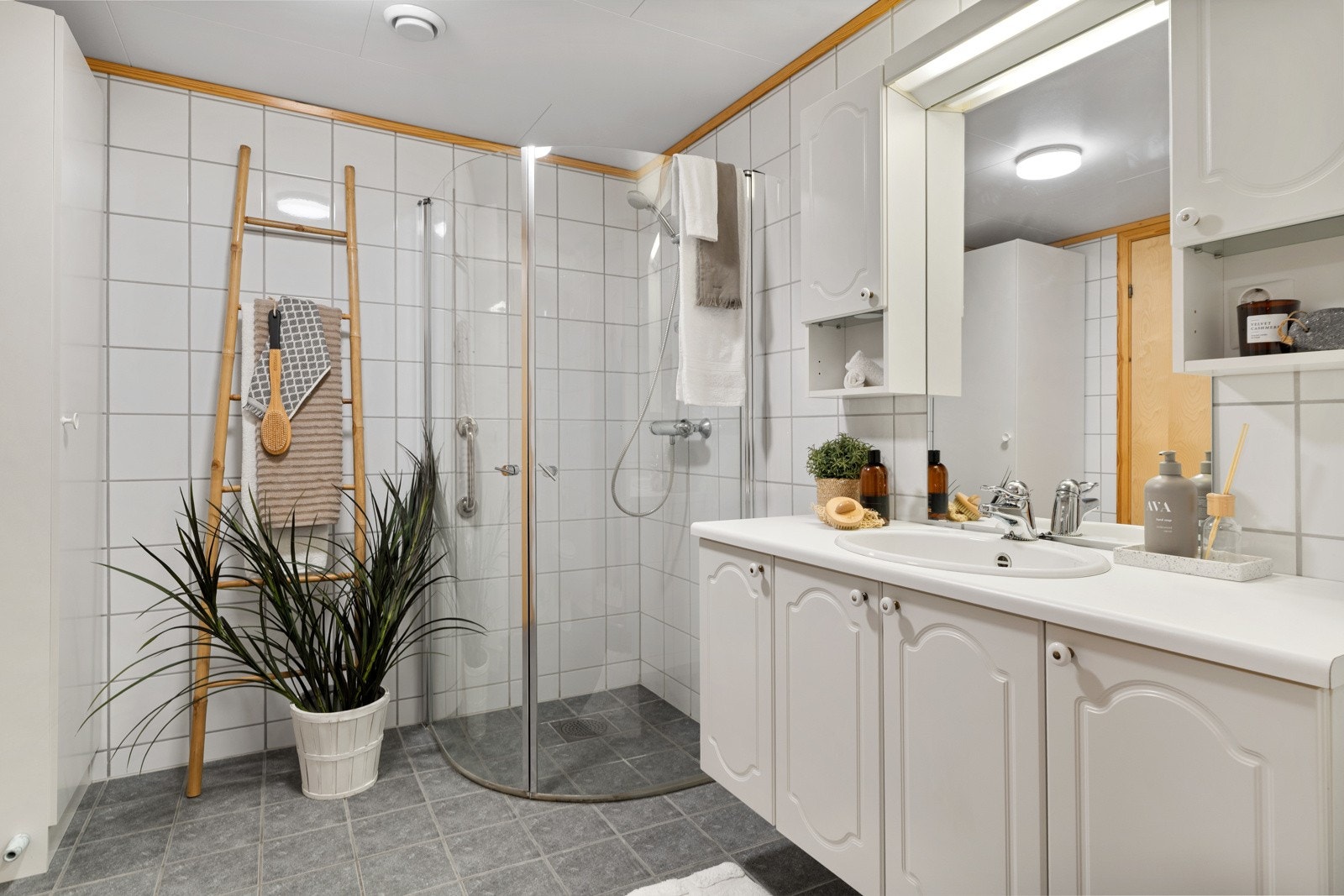 Flislagt baderom med varme i gulv på 6,5 kvm. Her er det romslig dusjhjørne med innfellbare dører og godt med oppbevaringsplass i badeomsinnredningen. Galleribilde