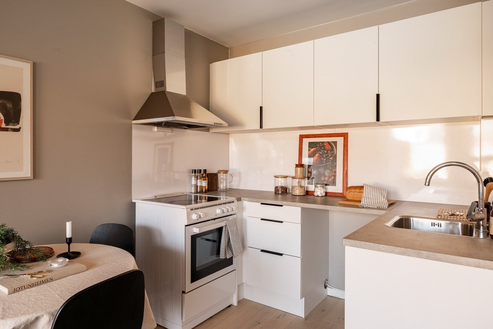 Hvit kjøkkeninnredning med glatte overflater og benkeplate av laminat. Galleribilde