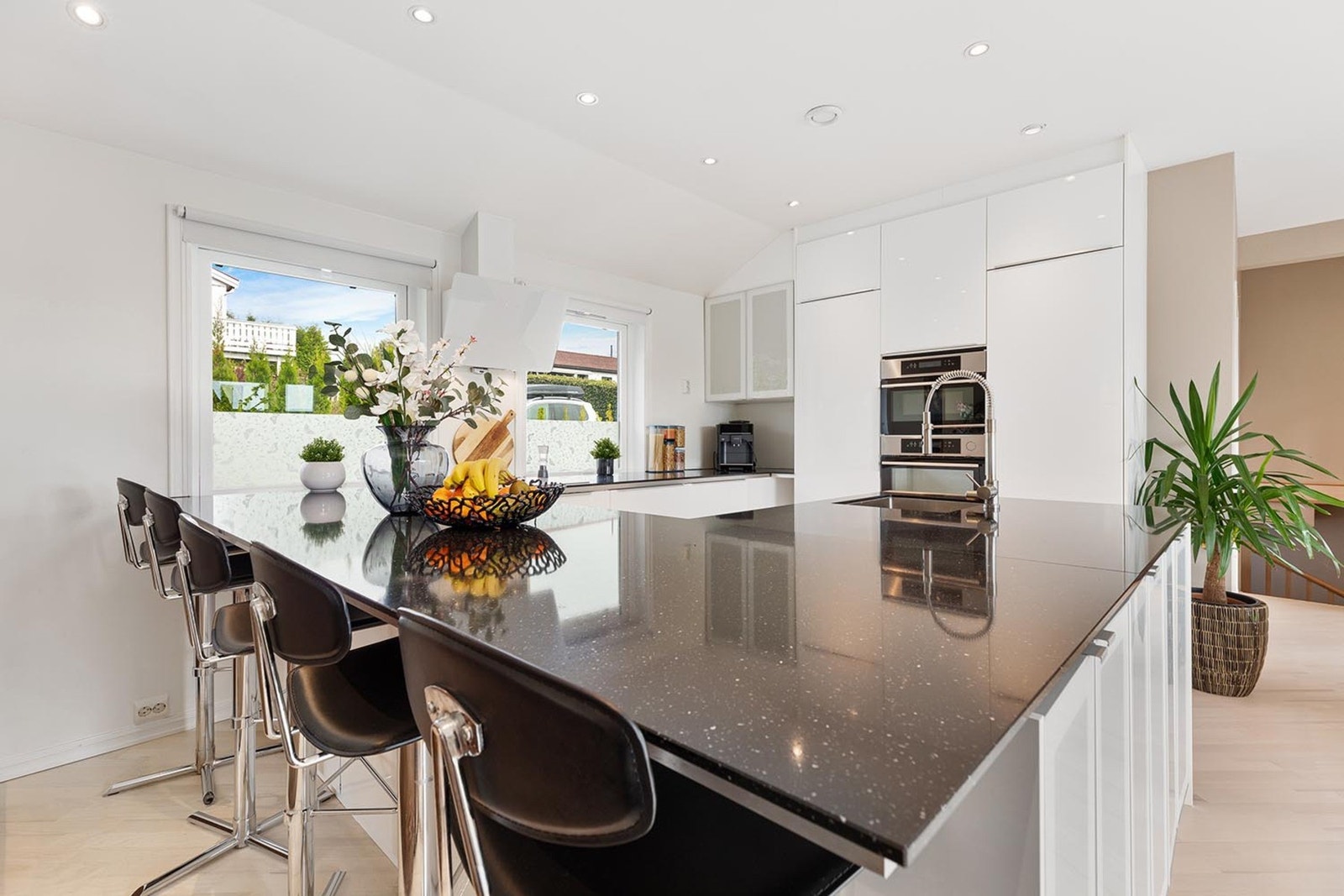 Med høyglans fronter og benkeplate i stein, gir det både stil og funksjonalitet Galleribilde