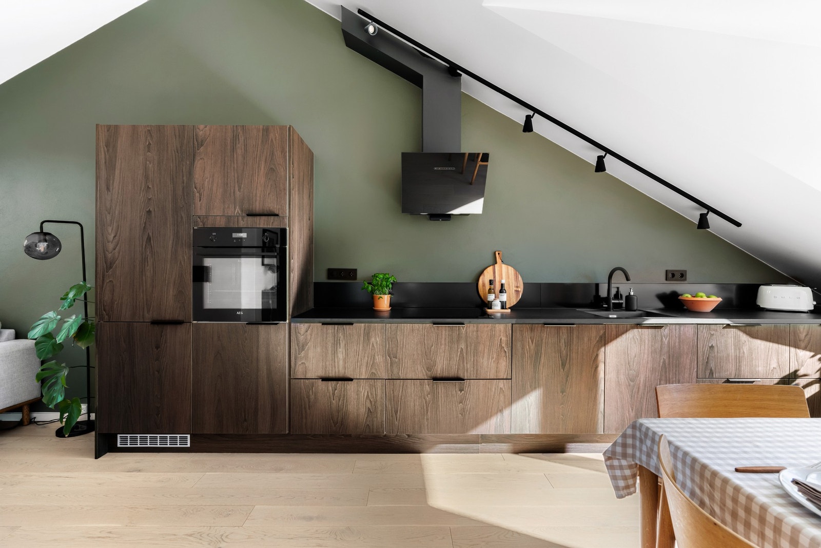 Rålekkert HTH kjøkken med valnøtt fronter, sort benkeplate, blandebatteri og kum samt lysskinne i tak med spotter Galleribilde