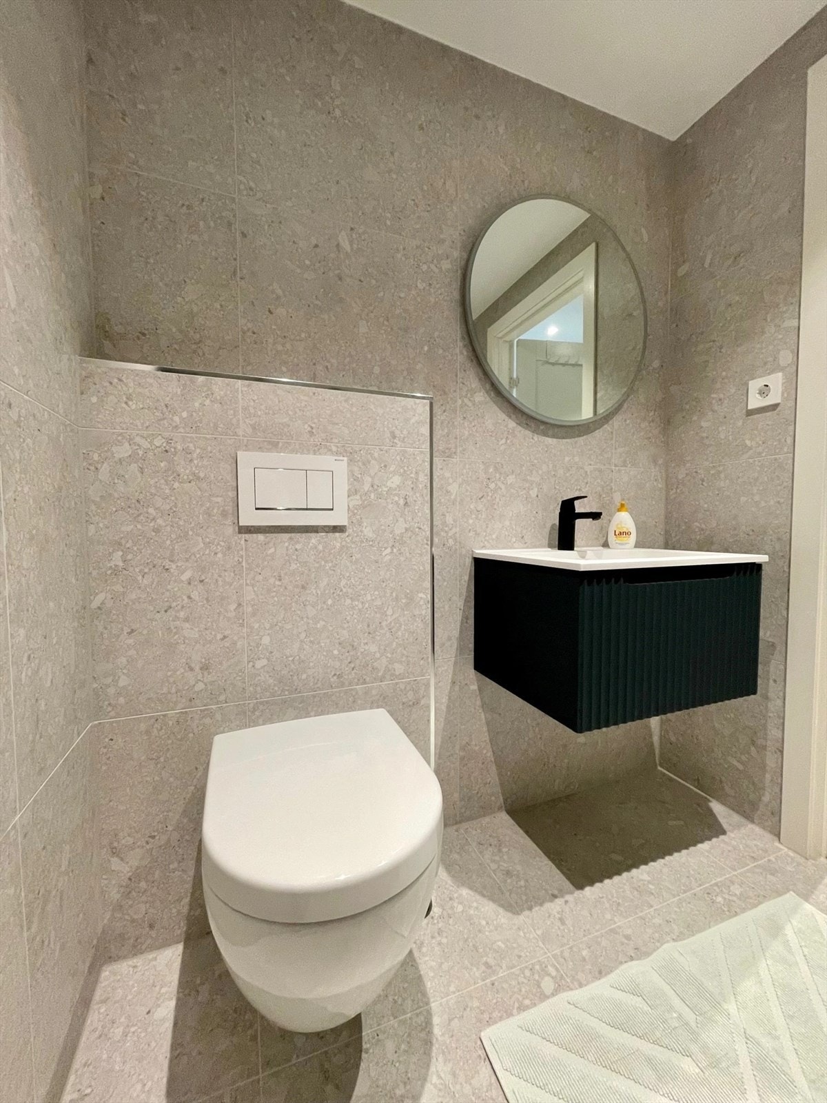 Innredet med servant, vegghengt toalett, dusj og speil med lys. Galleribilde