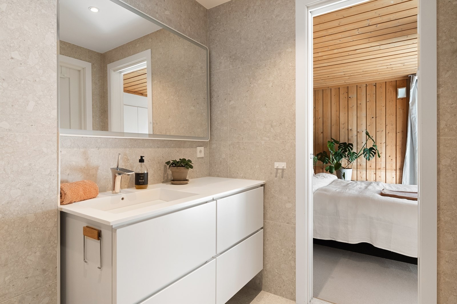 Badet er utstyrt med vegghengt toalett, dusj, belyst speil m/antidugg og baderomsinnredning med servant samt varmekabler i gulvet. Galleribilde