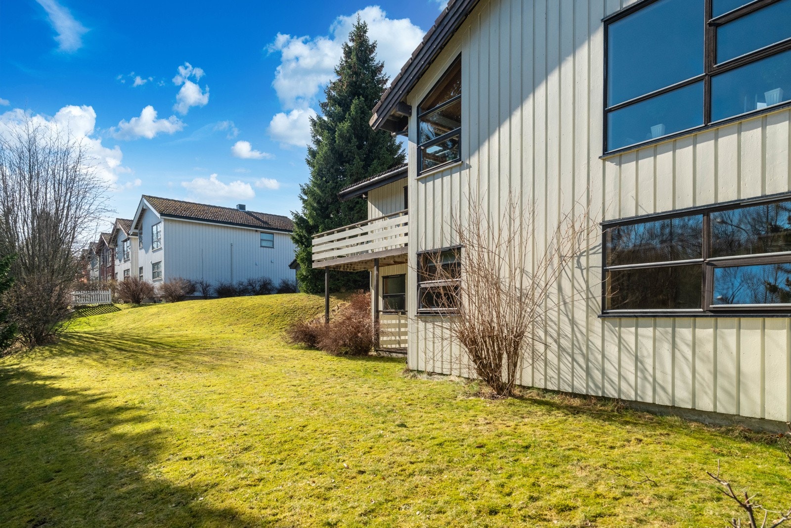 Tomten er solrik og har plen og beplantning på begge sider av huset. Galleribilde