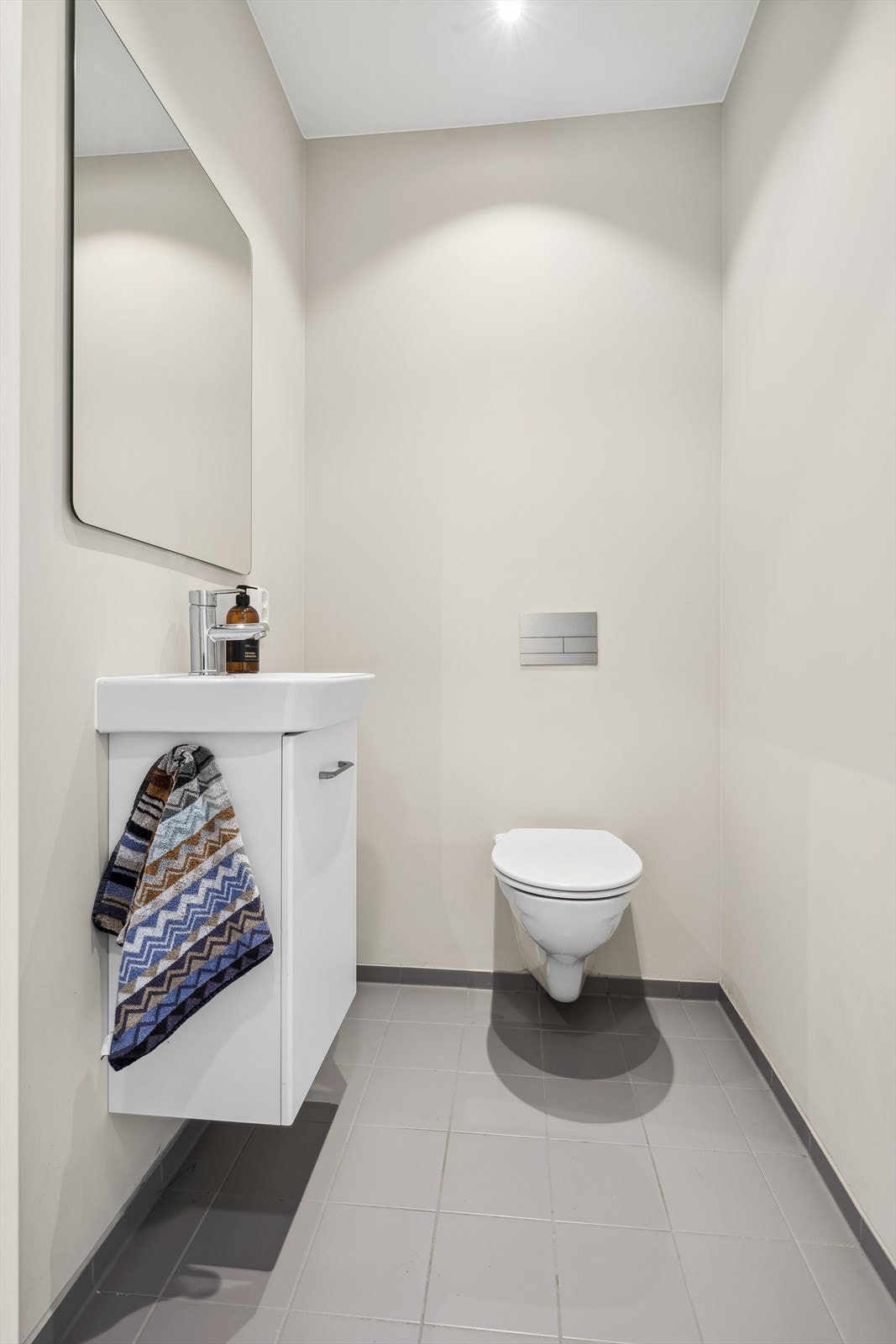 Det er for øvrig et separat toalettrom i boligens andre etasje. Rommet er gjennomført med fliser på gulvet og er innredet med vegghengt toalett, speil, spotbelysning i taket og baderomsinnredning med servant. Et meget praktisk rom i en hektisk hverdag! Galleribilde