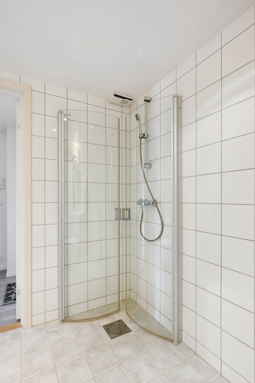 Badet er innredet med vegghengt toalett og dusjhjørne med innfellbare glassdører Galleribilde