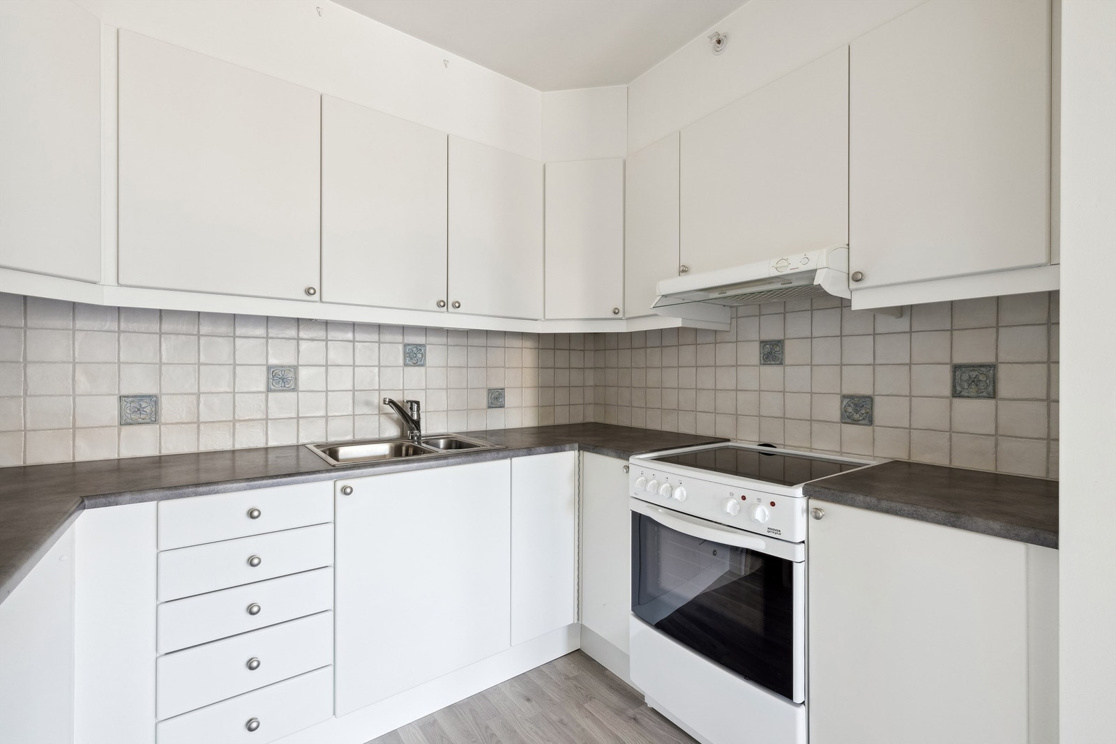 Kjøkken med innredning i profilerte fronter, benkeplate av laminat og frittstående hvitevarer Galleribilde