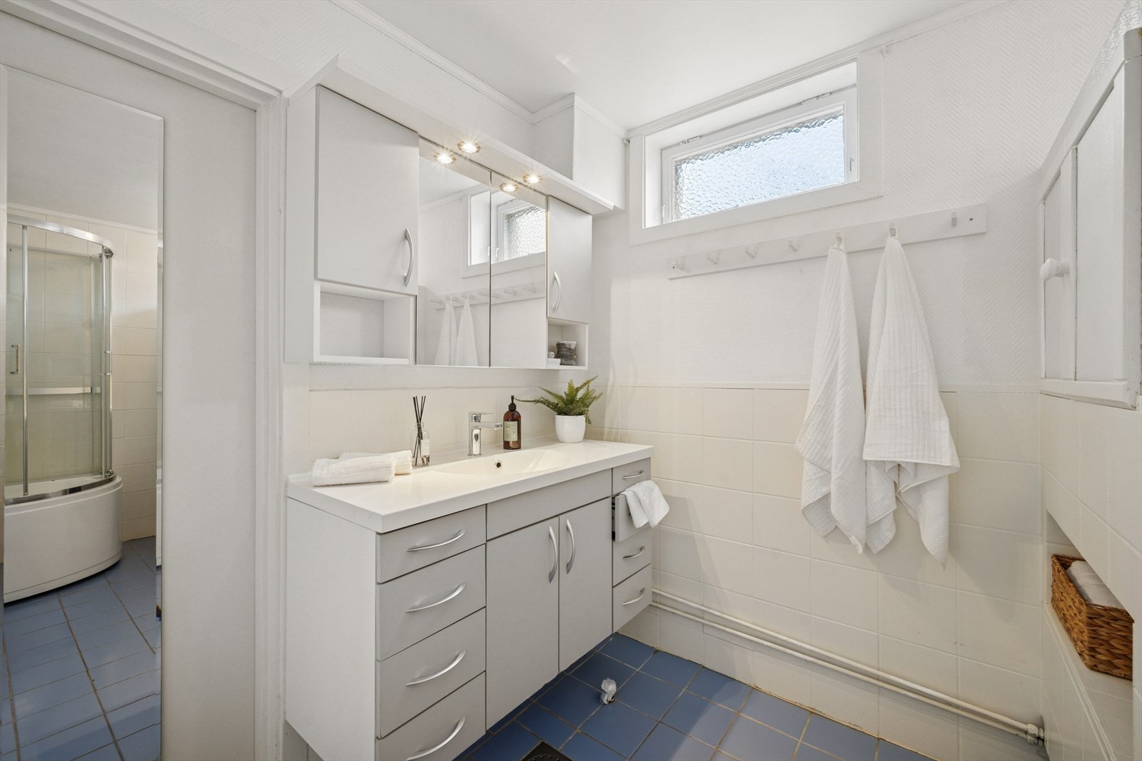 Badet er innredet med dusjkabinett med glassdører og baderomsinnredning med speilskap. Galleribilde