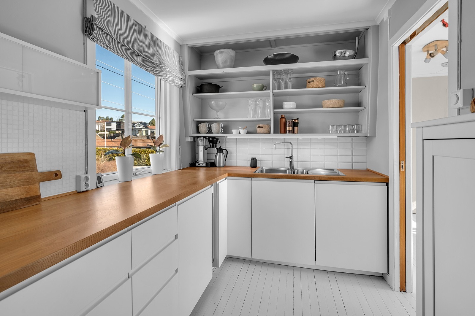 Kjøkken med lyse slette fronter benkeplate av tre. Galleribilde