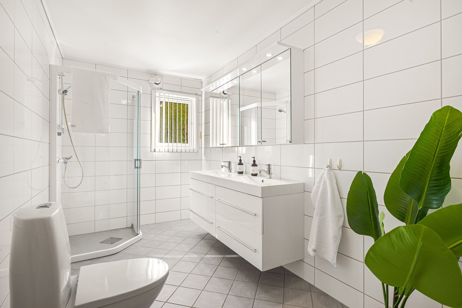 Baderommet i underetasjen har pene fliser på vegger og gulv, med varmekabler Galleribilde