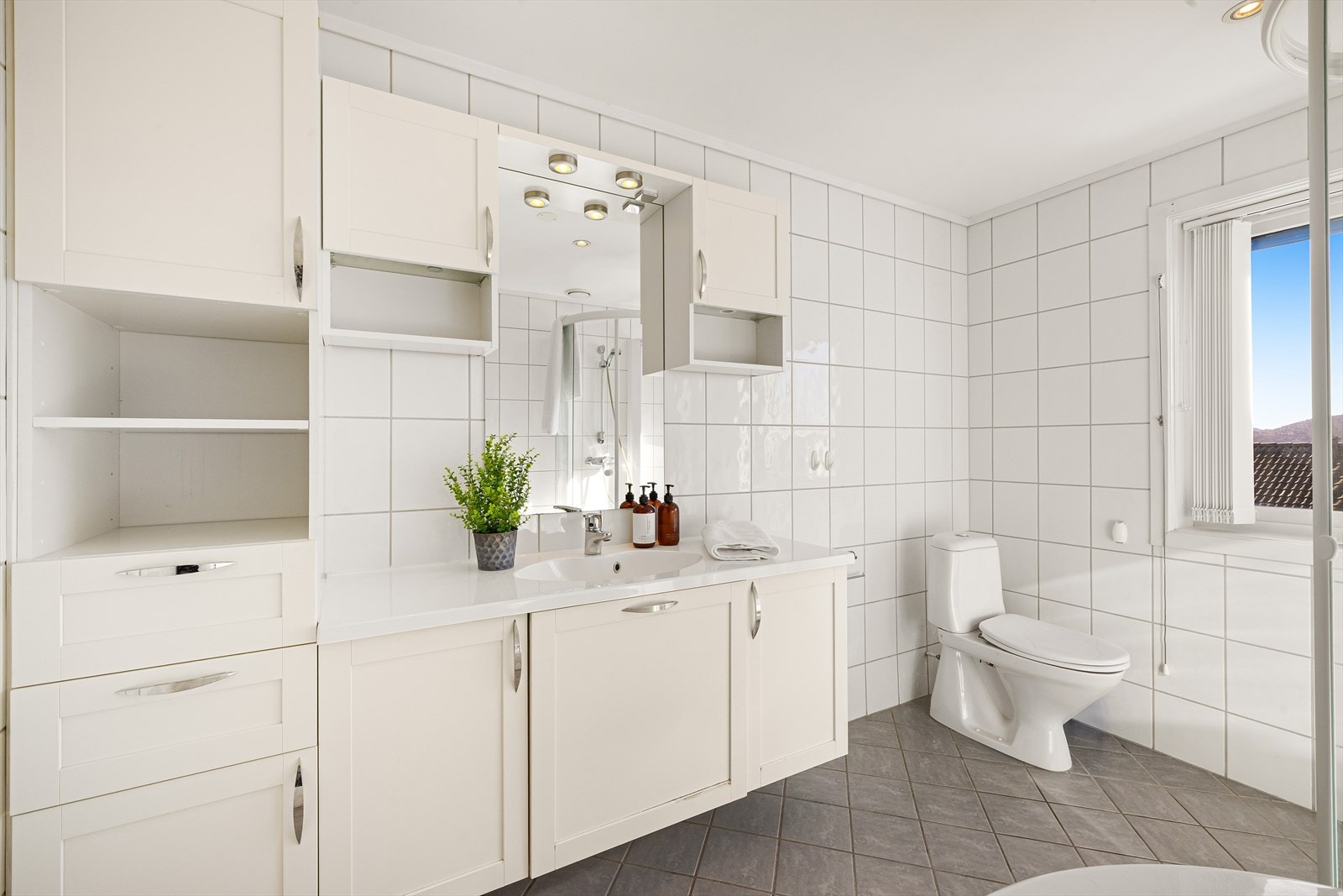 Baderommet i hovedetasjen ligger praktisk plassert i soveromsfløyen, og har tidsriktige, nøytrale fliser på vegger og gulv, med varmekabler Galleribilde