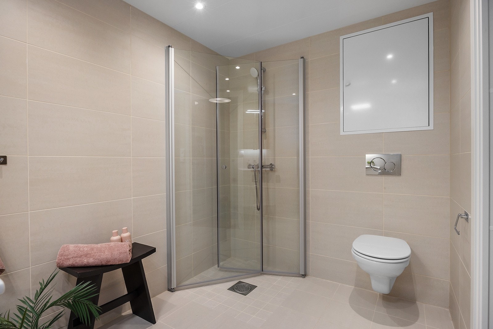 Delikat flislagt bad i beige farger med vannbåren gulvvarme og downlights i himling. Galleribilde