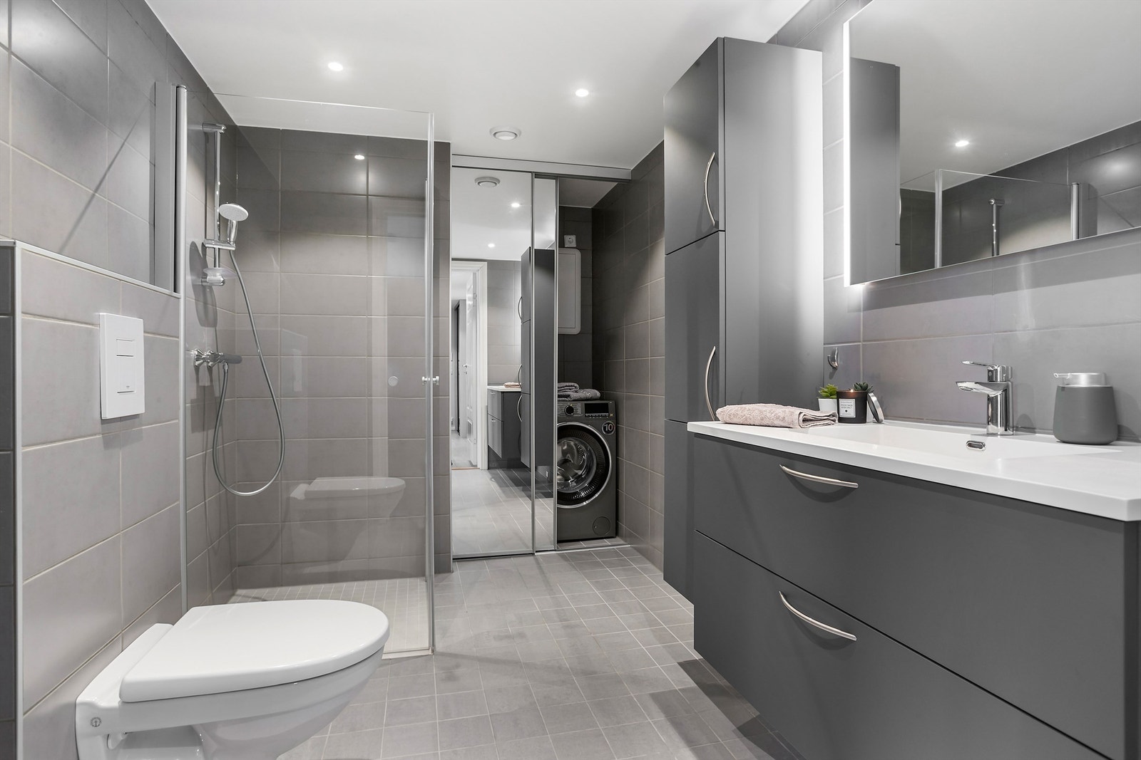 Flislagt bad med gulvvarme. Praktiske skyvedører med speil skjuler vaskemaskin og varmtvannsbereder Galleribilde