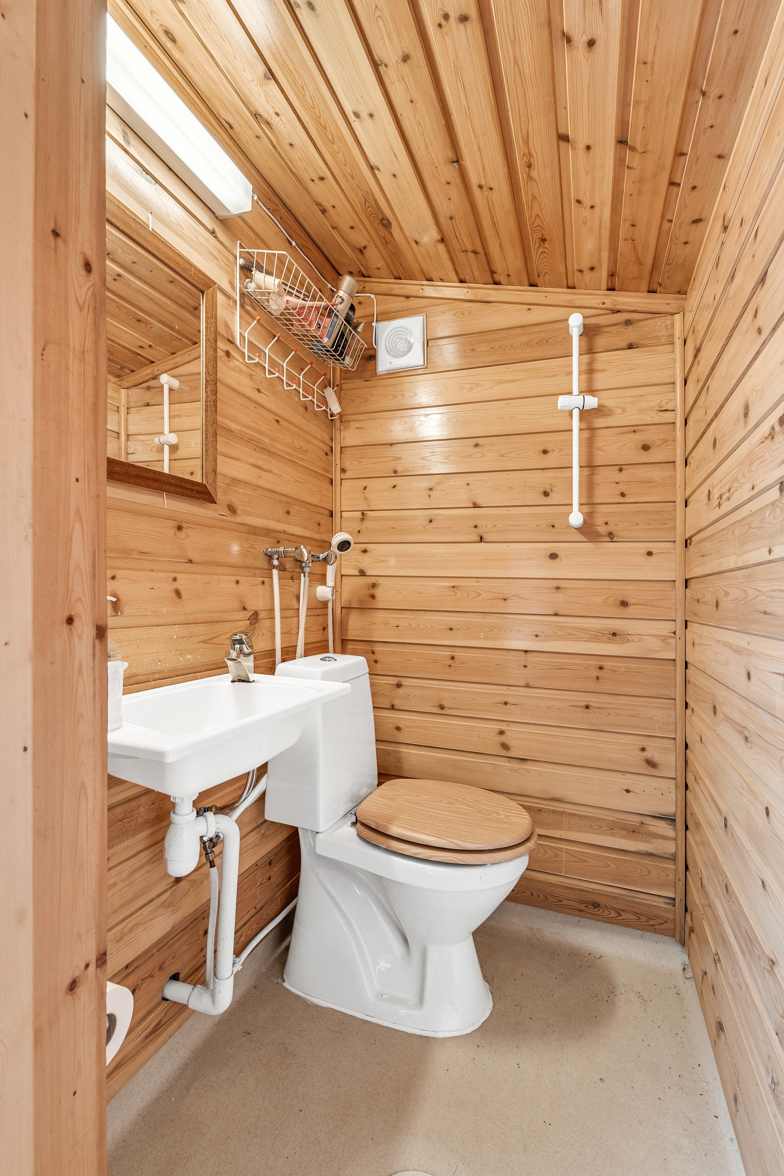 Bad med gulvstående toalett, vegghengt dusjarmatur og vegghengt servant. Galleribilde