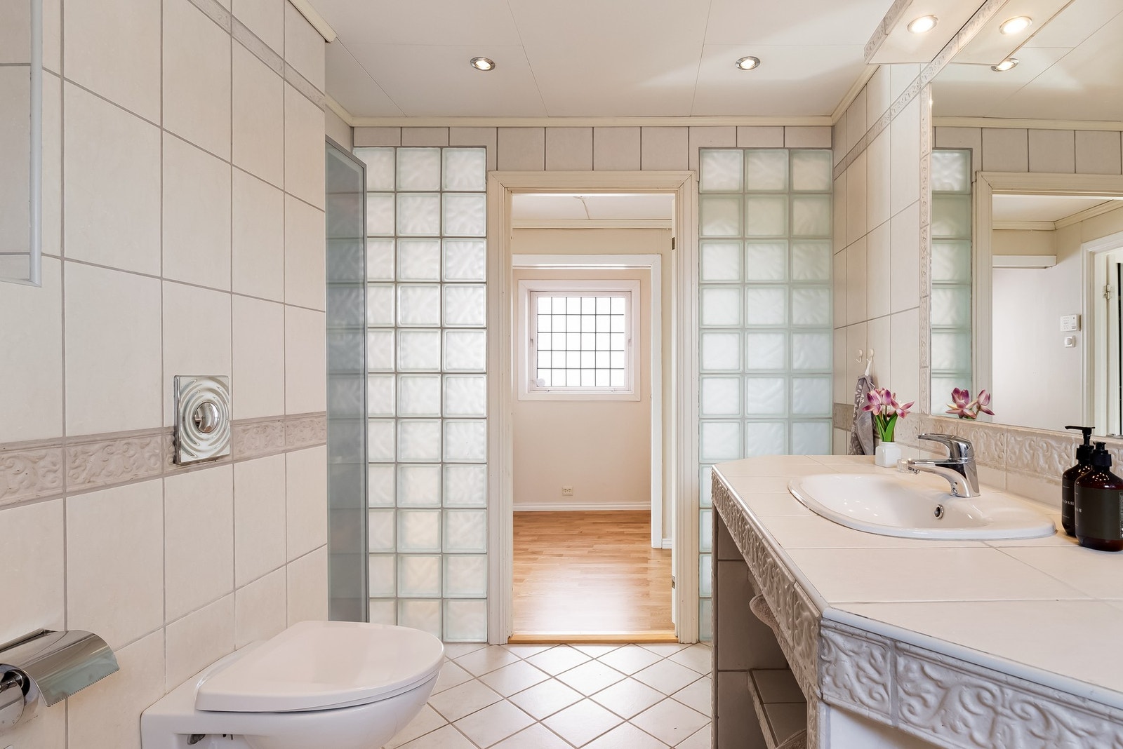 På badet er det en oppmurt/ flislagt seksjon med nedfelt servant, veggmontert toalett og innmurt badekar. Det er elektrisk styrt vifte. Glassbyggersten i vegg mot gang, samt frostet baderomsdør, gjør at det kommer lys inn til både badet og gangen utenfor Galleribilde