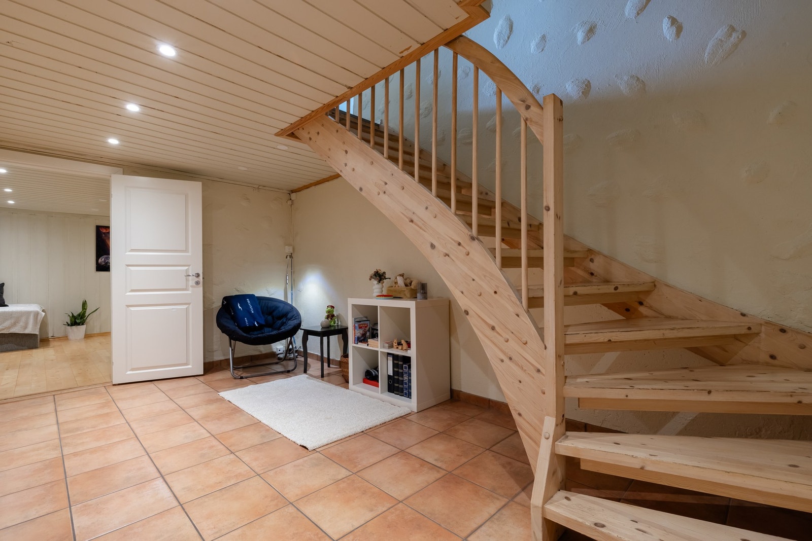 Vi trekker ned i kjelleren. Varmekabler, flislagt gulv og nye LED-downlights (2025) gjør hallen i kjelleren til et flott lekerom. Her kan barna både spille fotball og innebandy. Varmen i gulvet kan styres via app (Plejd). Også fint for firbente. Galleribilde