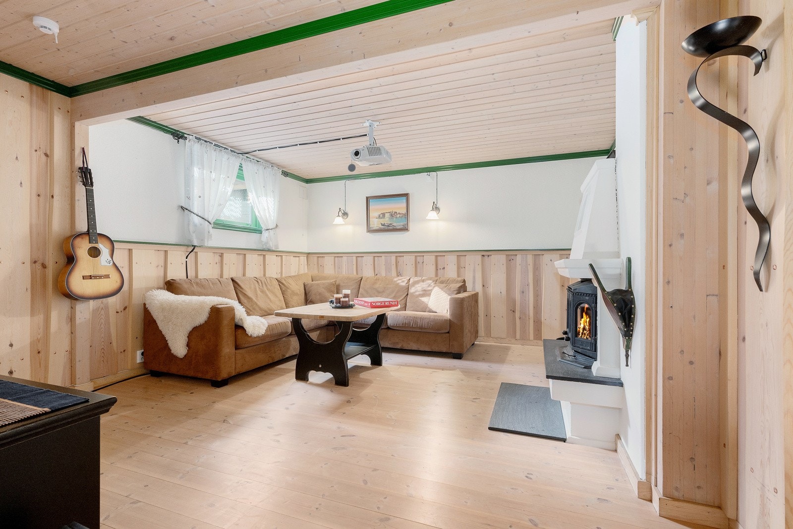 Disponibelt rom innredet som kjellerstue med peis Galleribilde