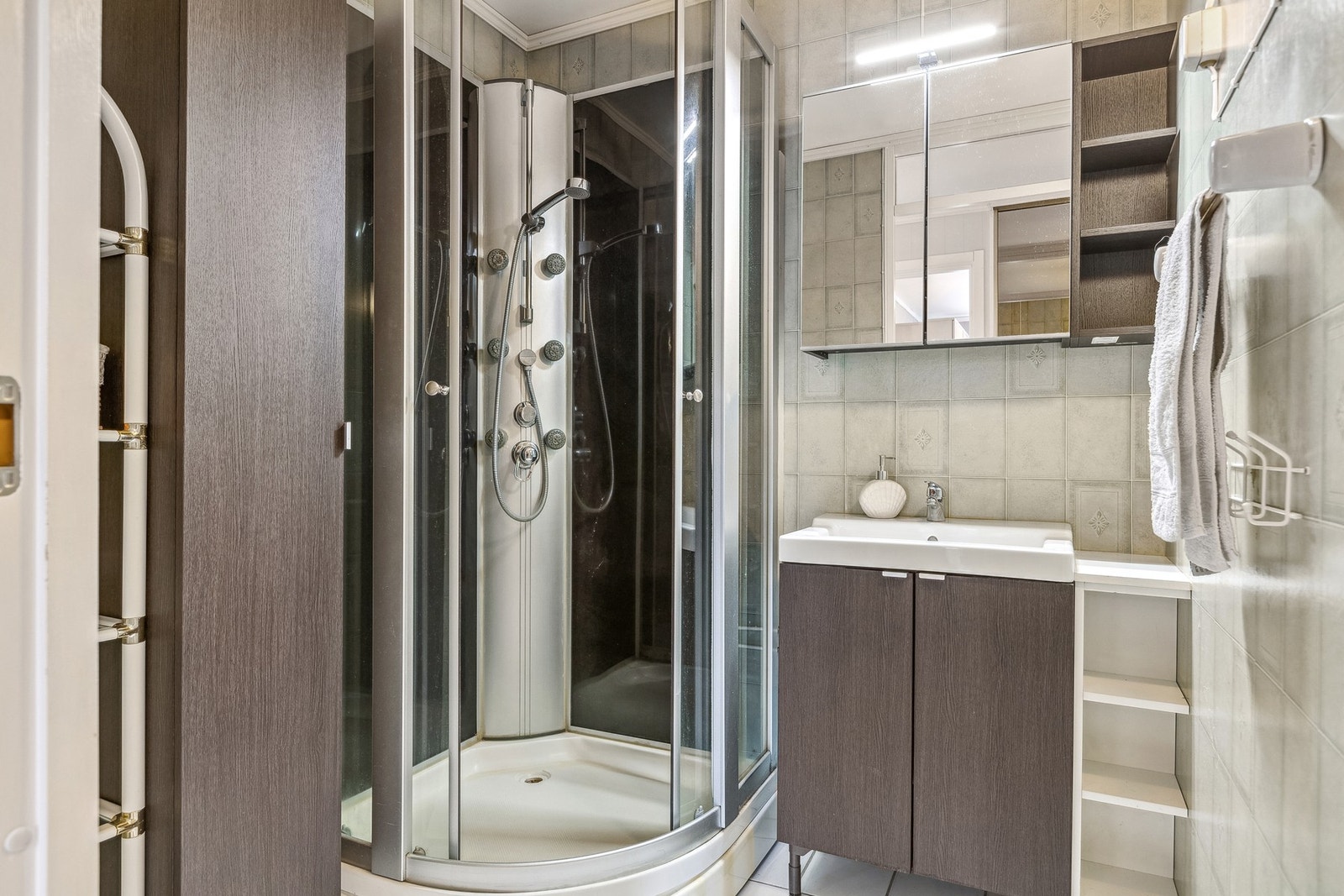 Baderommet er romslig med en moderne innredning, inkludert et praktisk dusjkabinett og et speilskap med innebygd lys. Galleribilde