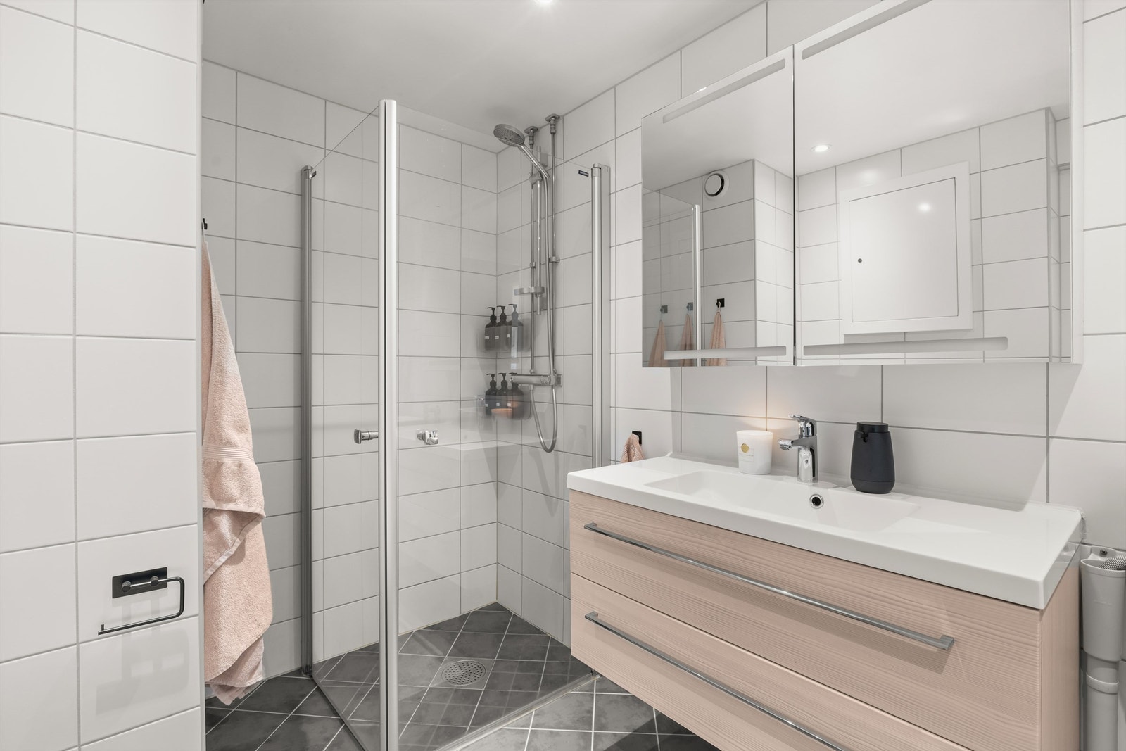 Badet er utstyrt med vegghengt innredning med heldekkende servant, overskap med speildører, dusjnisje med glassdører, vegghengt toalett og opplegg for vaskemaskin. Galleribilde