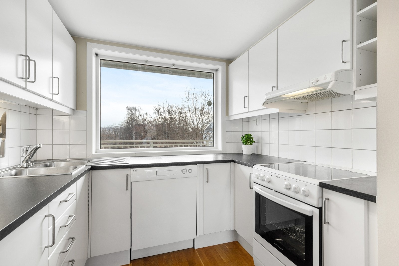 Hvite, glatte fronter og laminat benkeplate med nedfelt kum i rustfritt stål. Galleribilde