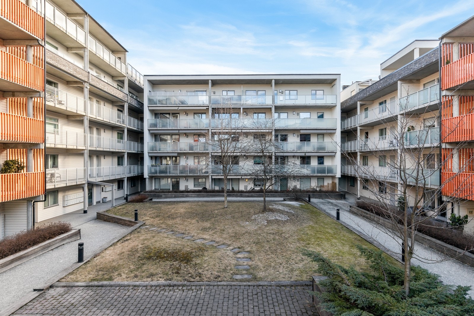 Felles atrium mellom bebyggelsen med steinbelagte internveier, belysning og store grøntområder med beplantning. Galleribilde