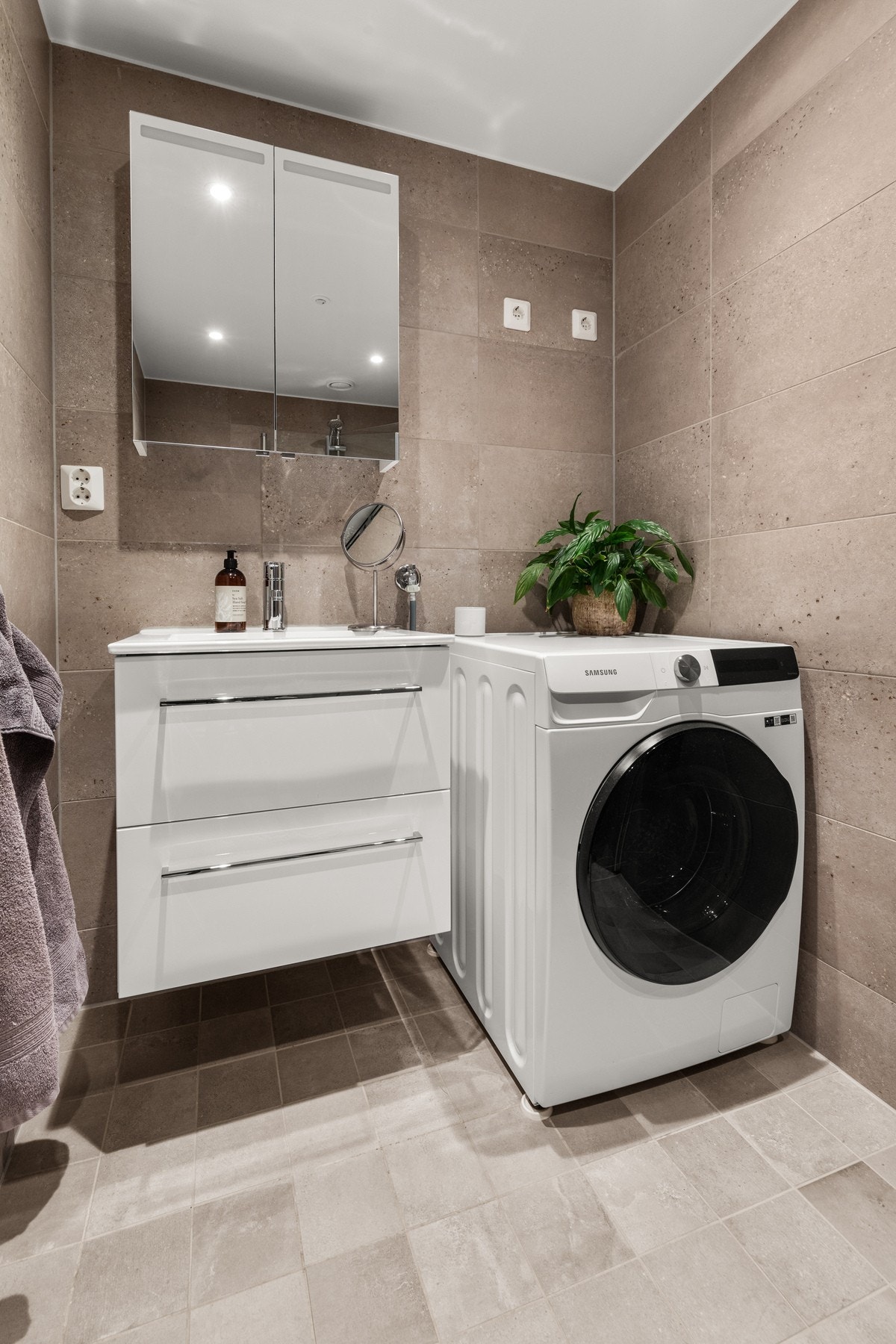 Benkeskap med glatte fronter og servant i helstøpt plate.Opplegg for vaskemaskin. Galleribilde