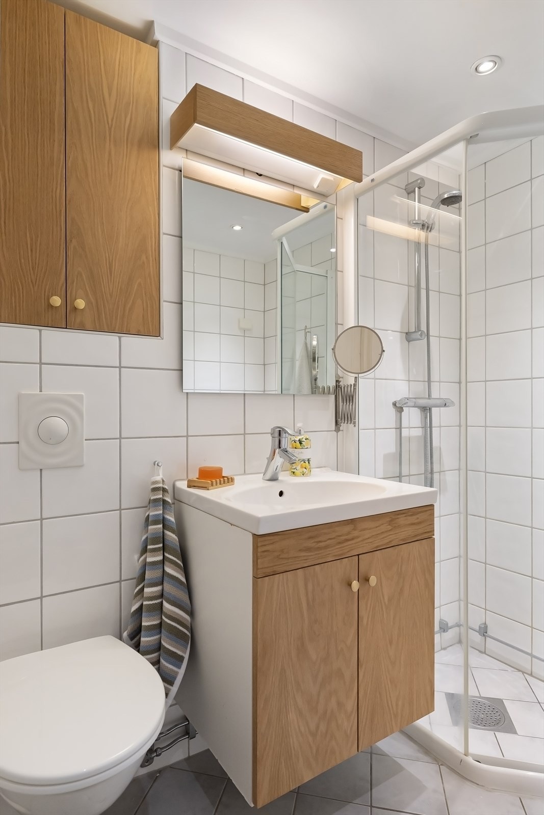Over servanten er det speil med belysning og et vegghengt skap. Dusjhjørne med skyvedører i glass og dusjarmatur tilkoblet veggmontert hånddusj. Praktisk med opplegg for vaskemaskin og tørketrommel. Galleribilde