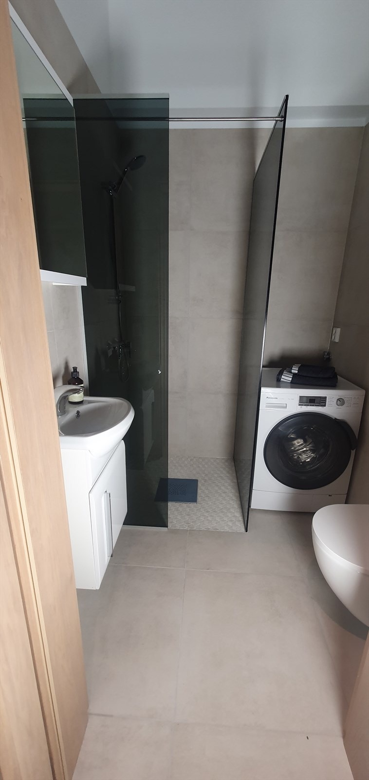 Rommet er innredet med dusj, toalett og servant, samt praktisk opplegg for vaskemaskin. De delikate materialvalgene og den gjennomtenkte planløsningen sørger for et funksjonelt og innbydende baderom med god komfort. Galleribilde