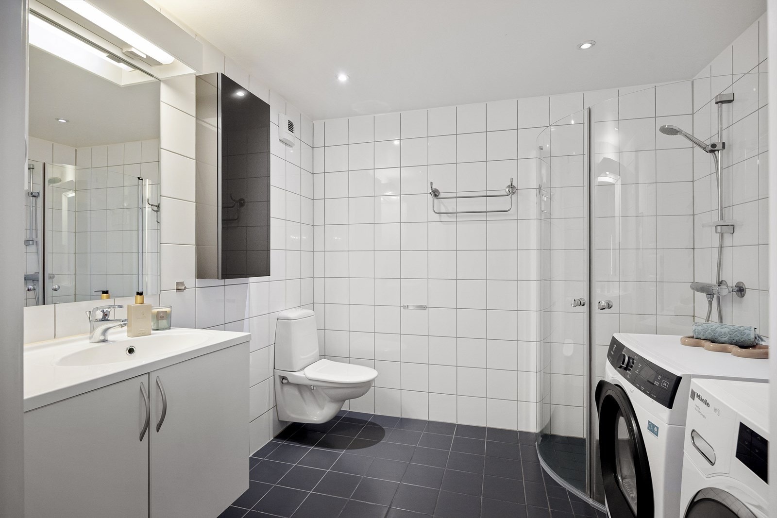 Pent og romslig flislagt baderom med gulvvarme og downlights i taket. Galleribilde