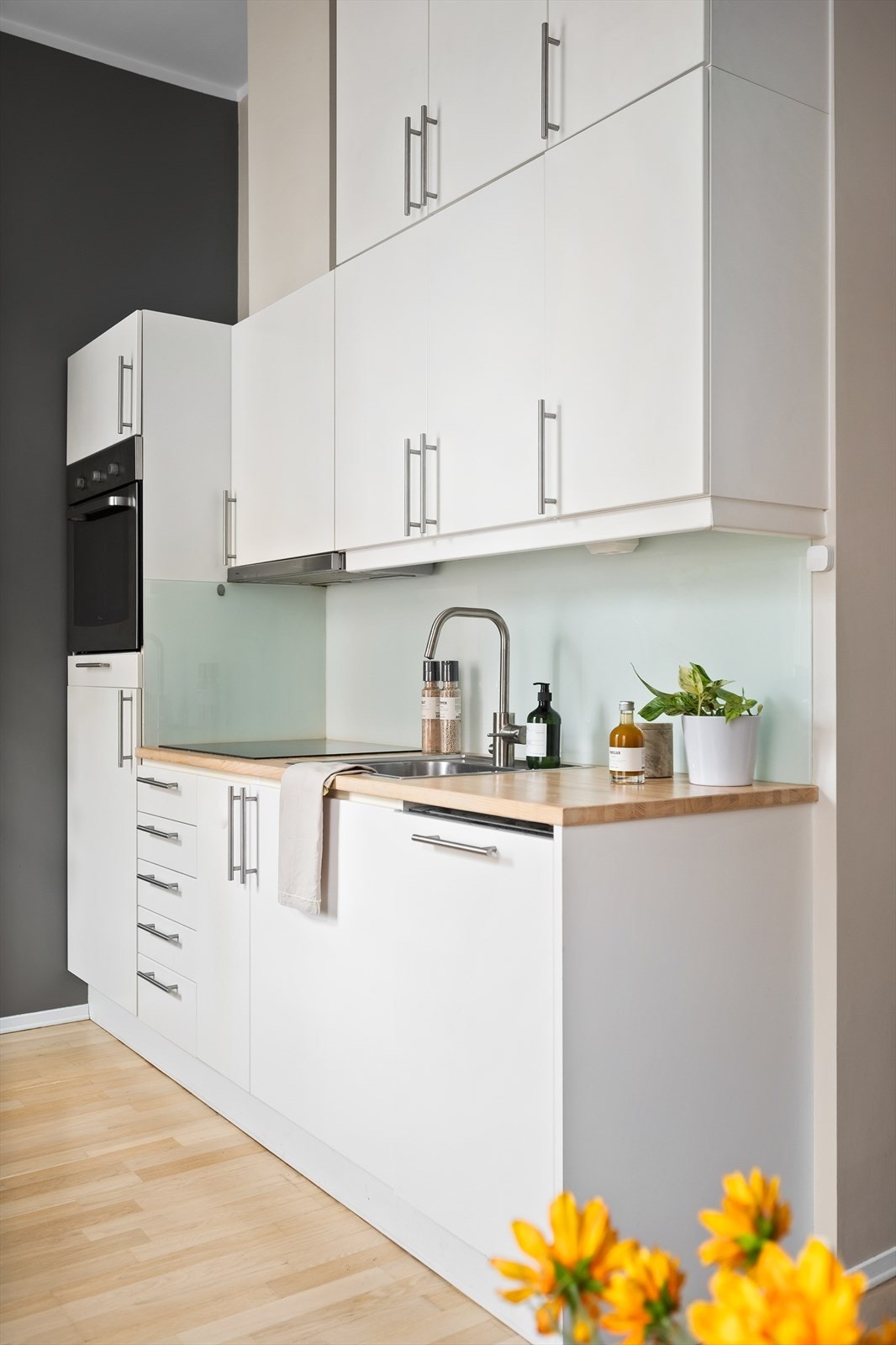 Moderne innredning med hvite, glatte fronter og benkeplate i heltre med nedfelt oppvaskkum og oppvaskmaskin. Galleribilde