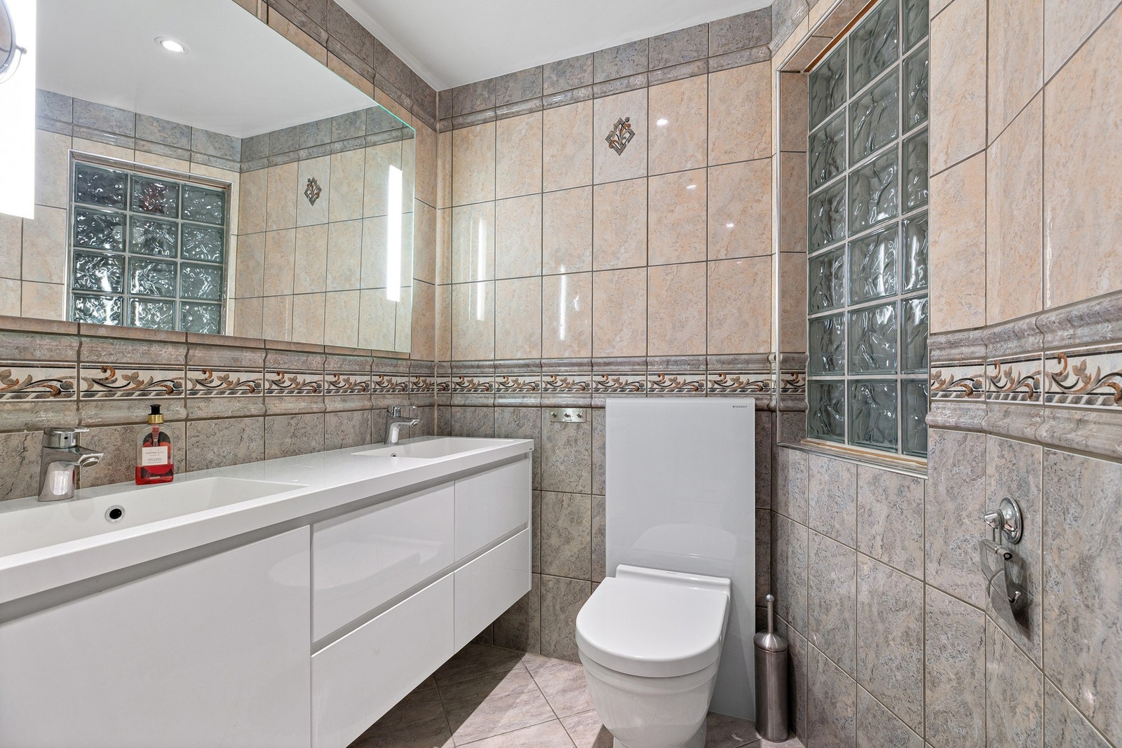 Badet er også innredet med 2 nedfelte servanter og et vegghengt toalett med utvendig sisterne Galleribilde