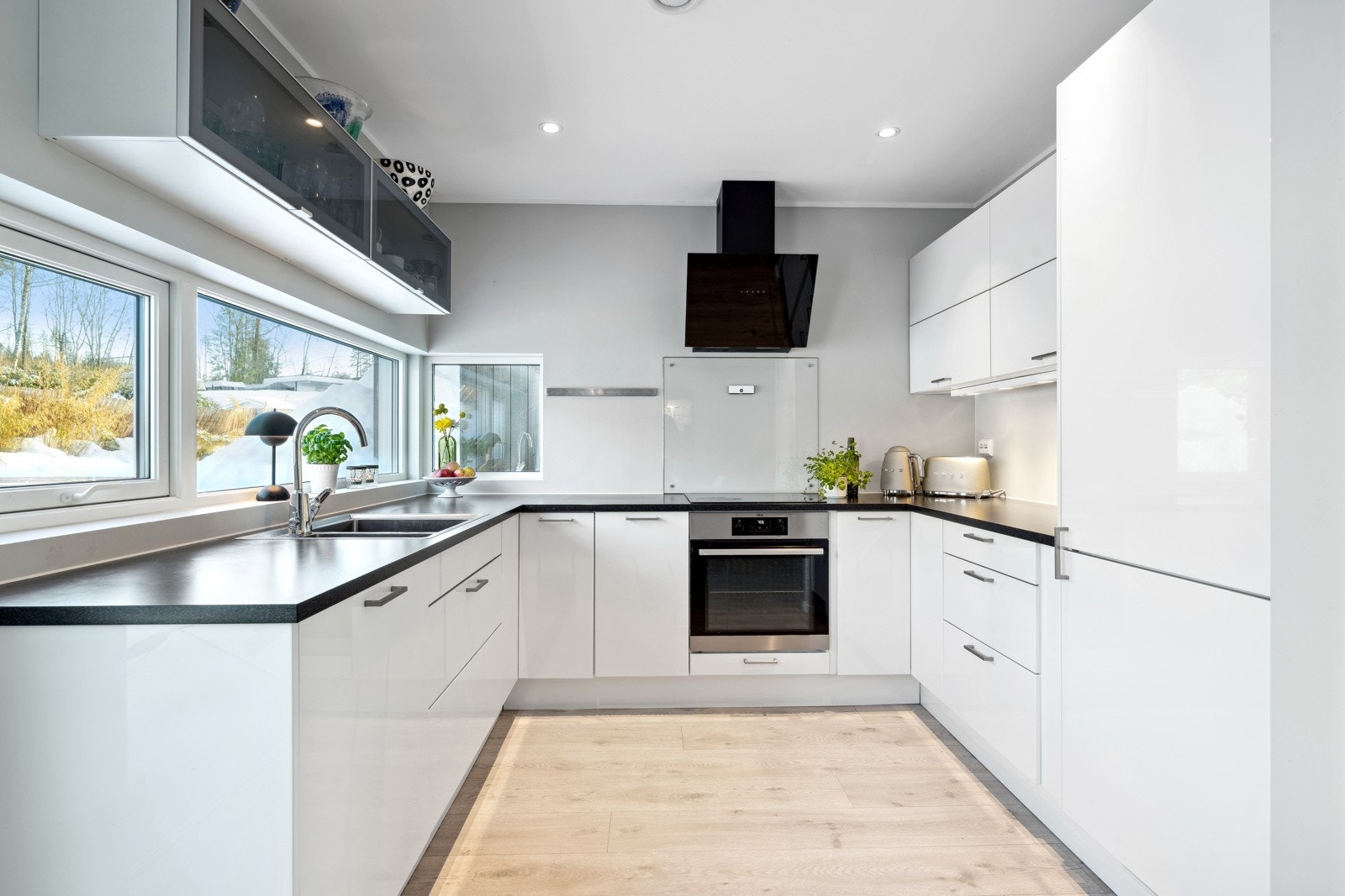 Moderne kjøkken i bakkant av stuearealene med mye lysinnslipp og lite innsyn. Galleribilde