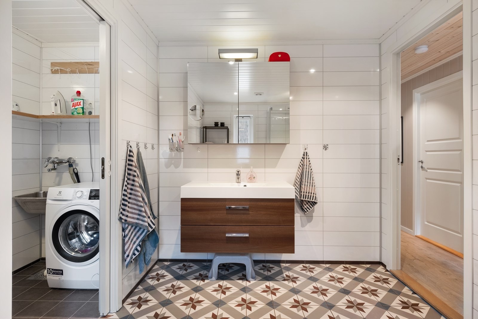 - Badet hat flislagt golv med varme og baderomsplater på veggane. Utstyrt med vegghengt toalett, dusjkabinett, servant og speilskap - Galleribilde