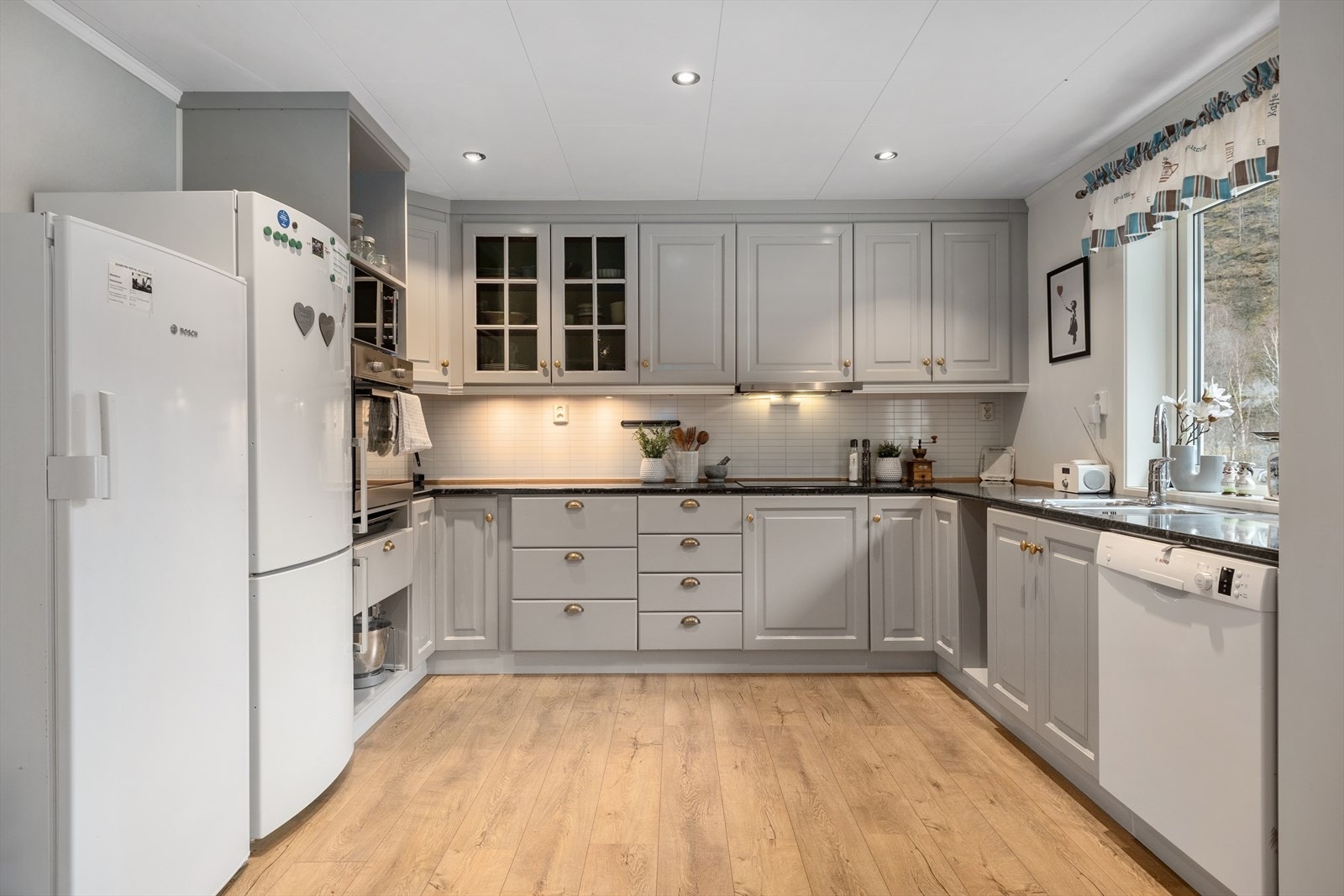 - Kjøkkenet har innredning med profilerte fronter. Benkeplaten er av
laminat. Kvitevare som ppvaskmaskin, platetopp og steikeovn - Galleribilde