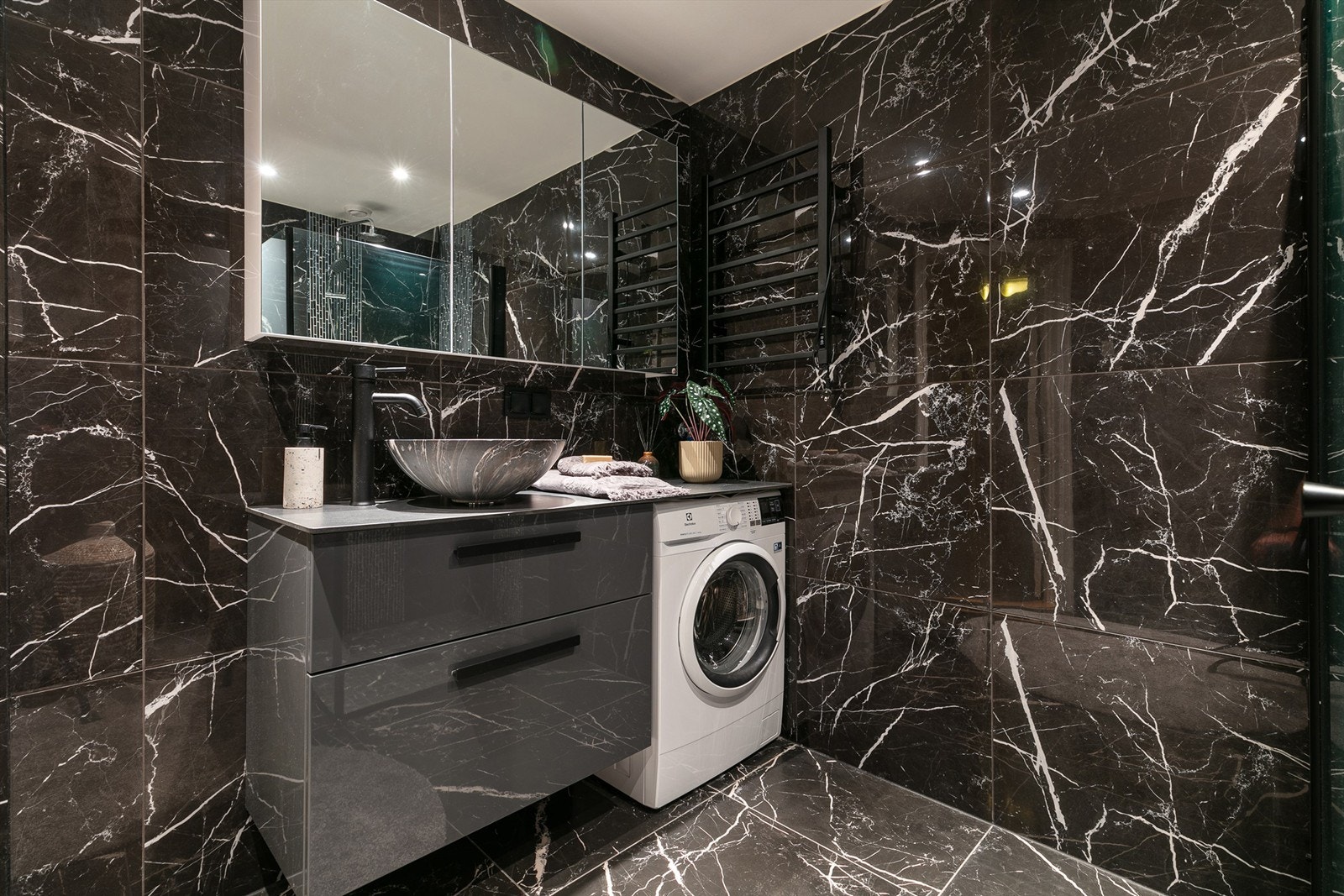 Baderommet er gjennomført med opplegg for vaskemaskin, servant med underskap og speilskap med belysning. Galleribilde