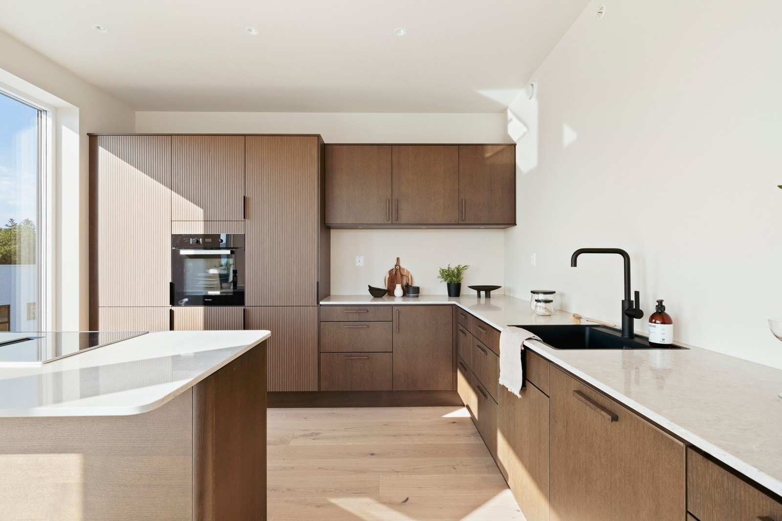 Utenom en flott barløsning, er innredningen av typen Favn Nøtt oppført i en funksjonell L-form med god arbeidsflyt, glatte fronter i eik og rillede høyskap. Galleribilde