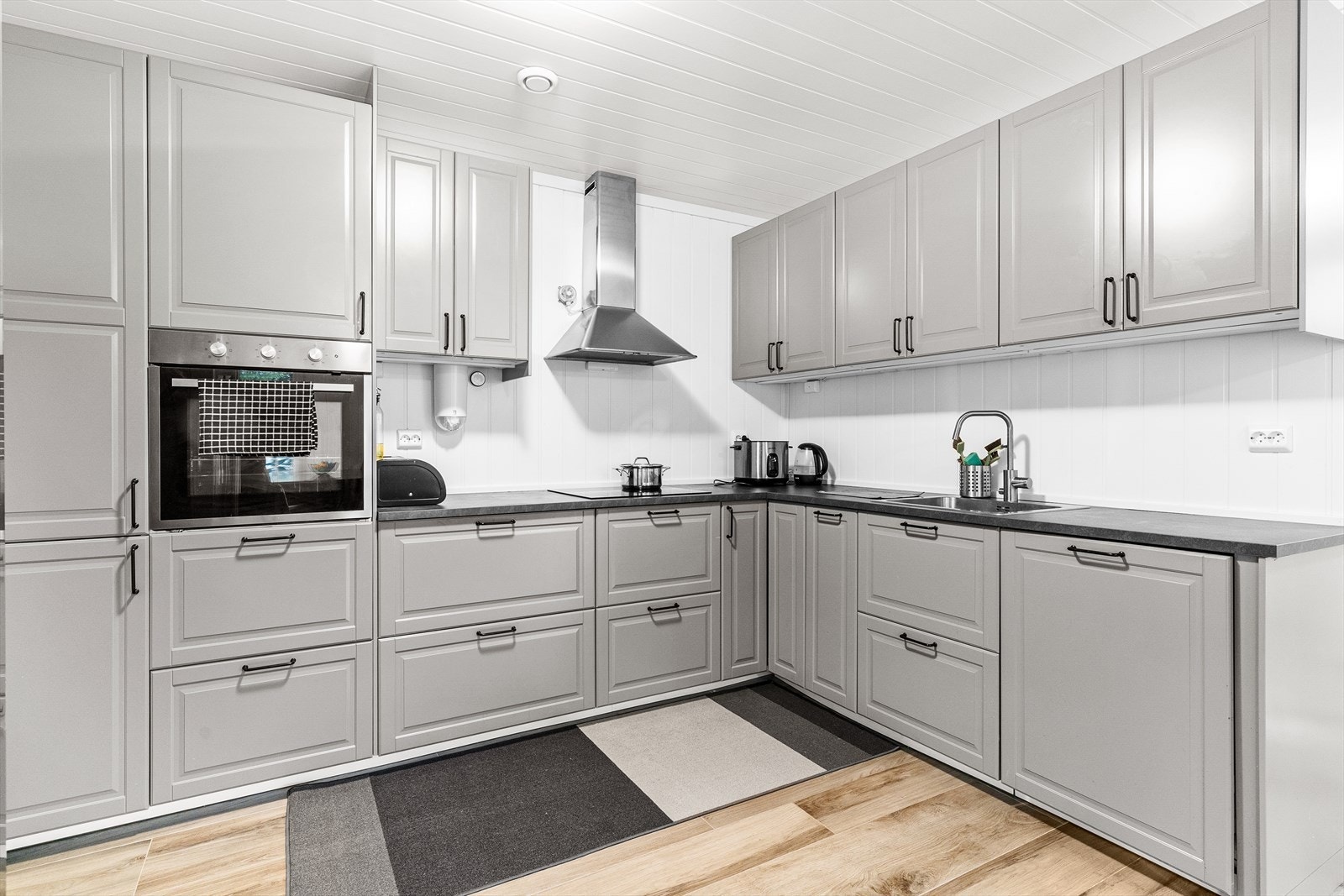 Klassisk og elegant kjøkkeninnredning i underetasjen fra Ikea med grå, profilerte fronter og benkeplate av laminat. Galleribilde