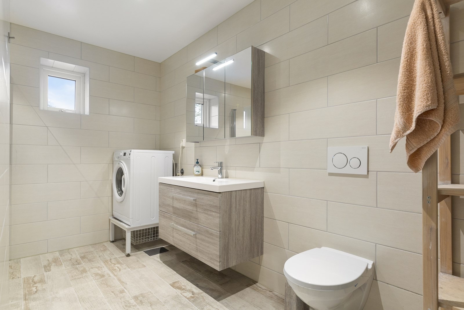 Baderommet er praktisk utstyrt med vegghengt toalett, baderomsinnredning, dusjhjørne og opplegg for vaskemaskin. Galleribilde